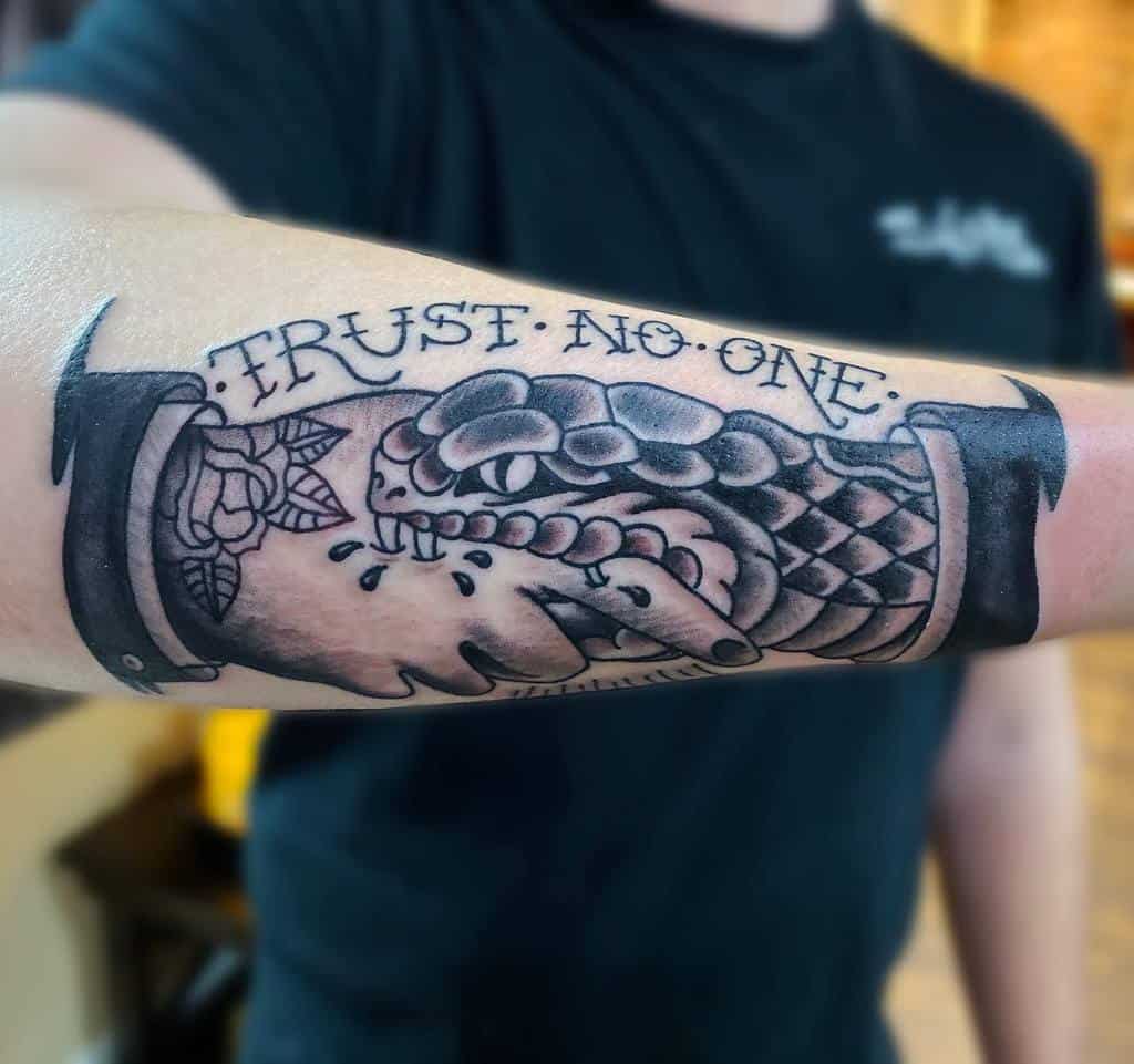 Forearm tattoo of a snake and handshake with the words "Trust No One" above it