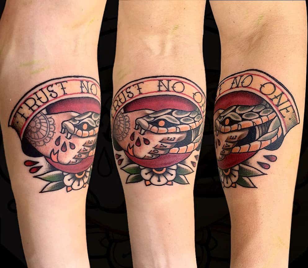 Traditional-style tattoo of a handshake between a human and a snake with blood drops, surrounded by a banner that reads 'Trust No One' and floral accents below