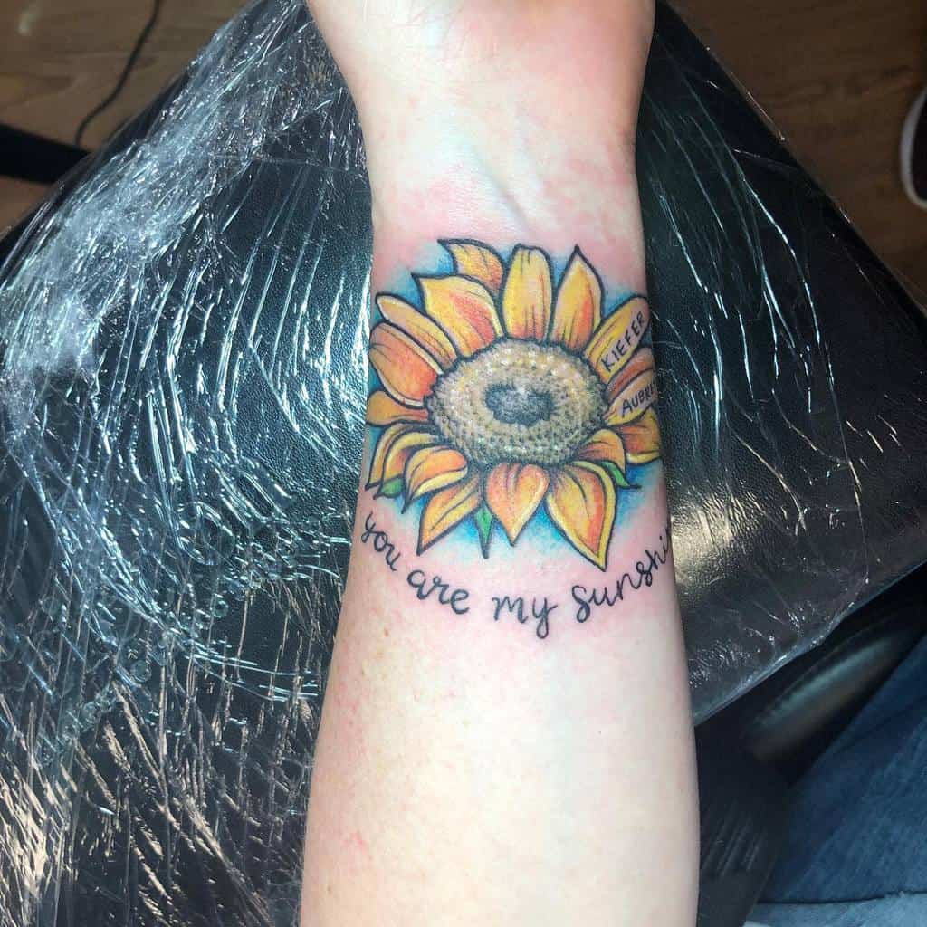 Sunflower tattoo on forearm with "you are my sunshine" text