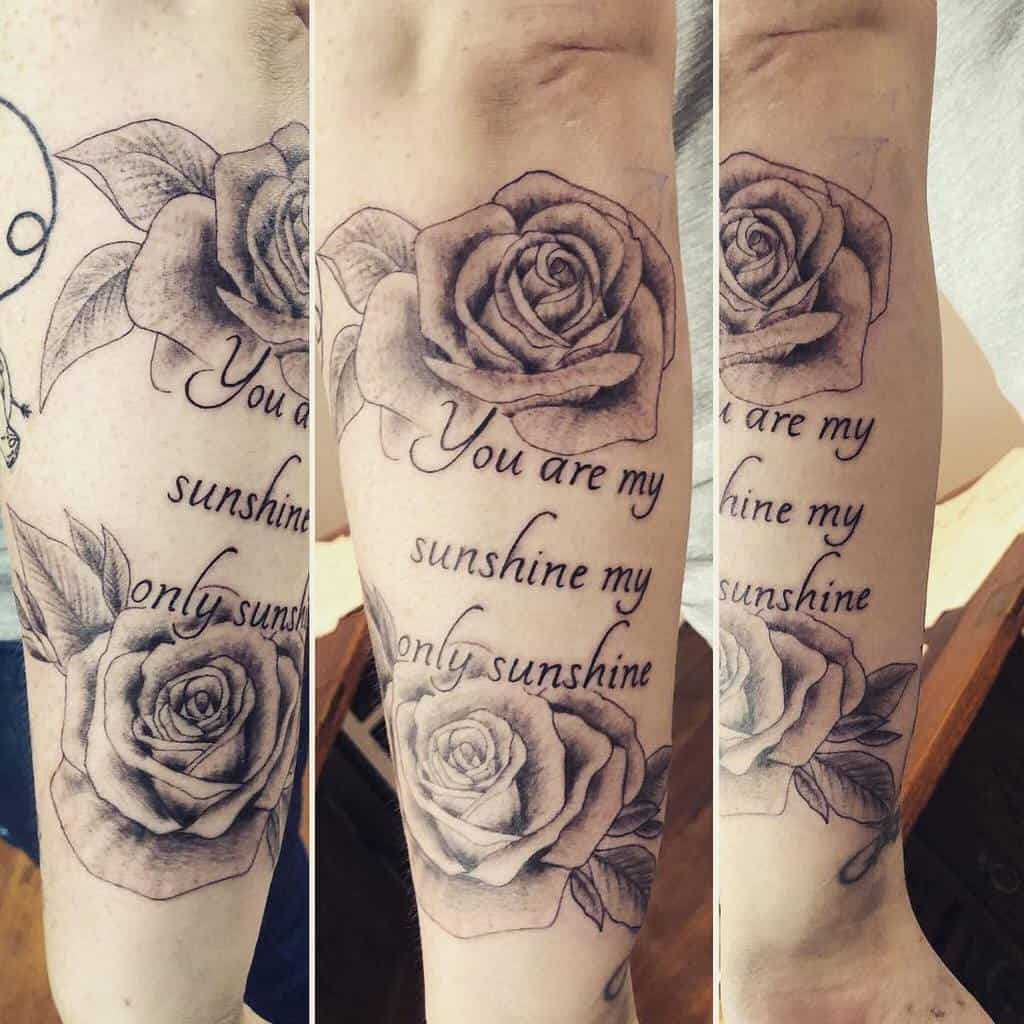 Tattoo of roses with "You are my sunshine, my only sunshine" text on a person's arm
