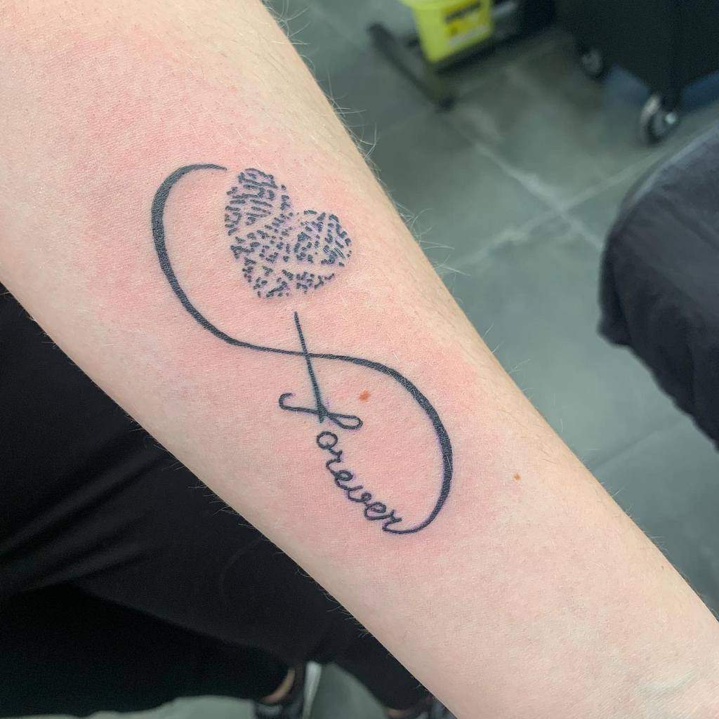 A meaningful infinity tattoo featuring a heart made of fingerprint patterns and the word "forever" below, symbolizing eternal love and connection.