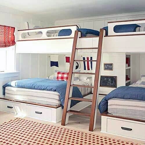 Bright bunk bed setup with navy and red nautical-themed bedding, wooden ladder, and built-in drawers for storage