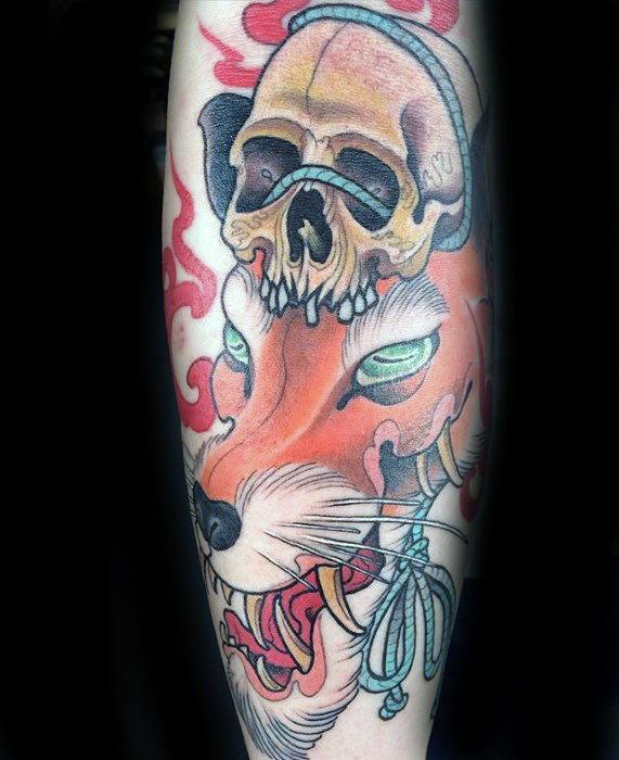 Colorful Japanese-style tattoo of a fierce fox with glowing eyes, a skull on its head, and swirling red smoke elements.