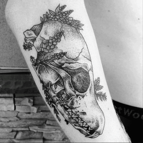 Dotwork tattoo of a fox skull with leaves and flowers woven through, blending natural elements with anatomical detail.