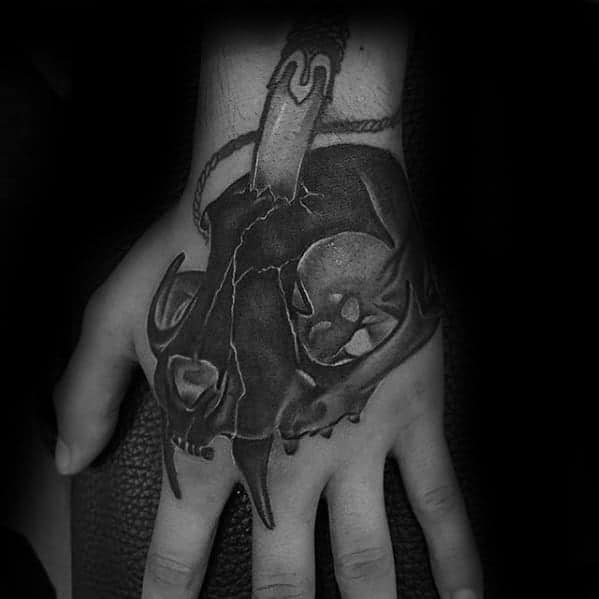 Tattoo of a black skull and snake on the back of a person's hand