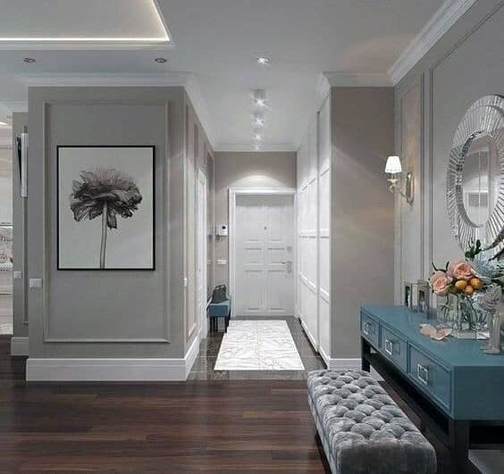 Stylish foyer with crown molding lighting, elegant furniture, and modern artwork for a welcoming ambiance