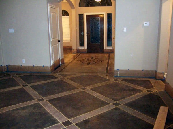 Room with arched doorway, decorative tile flooring, beige walls, and a large wooden front door with concrete panels
