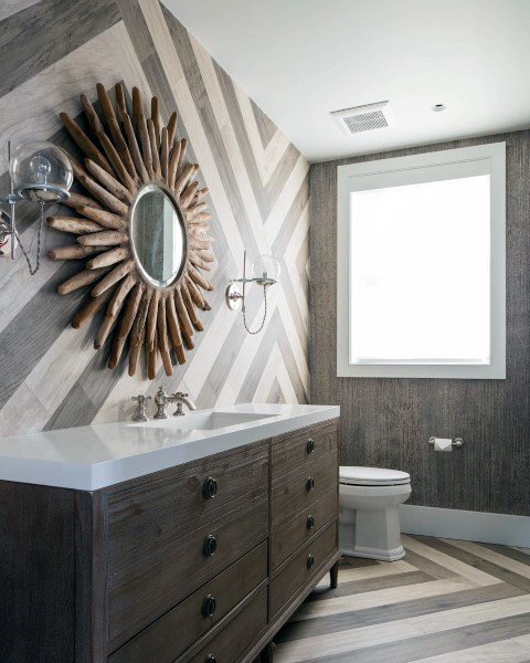 Rustic bathroom with driftwood-framed mirror, chevron-patterned walls, and wooden vanity.