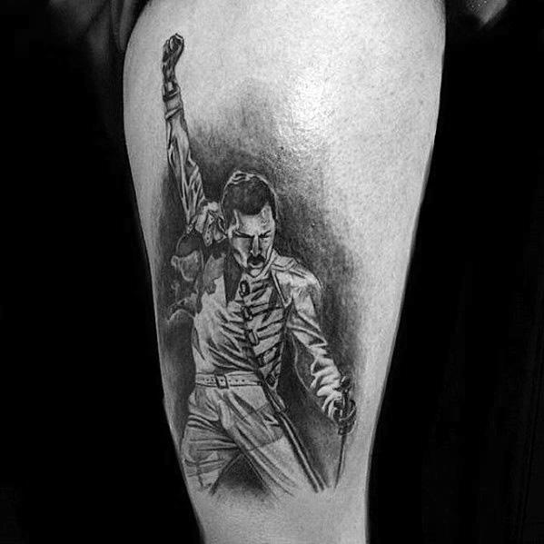Black and grey tattoo of Freddie Mercury in his iconic pose with raised fist and microphone, showcasing dynamic energy and detail.