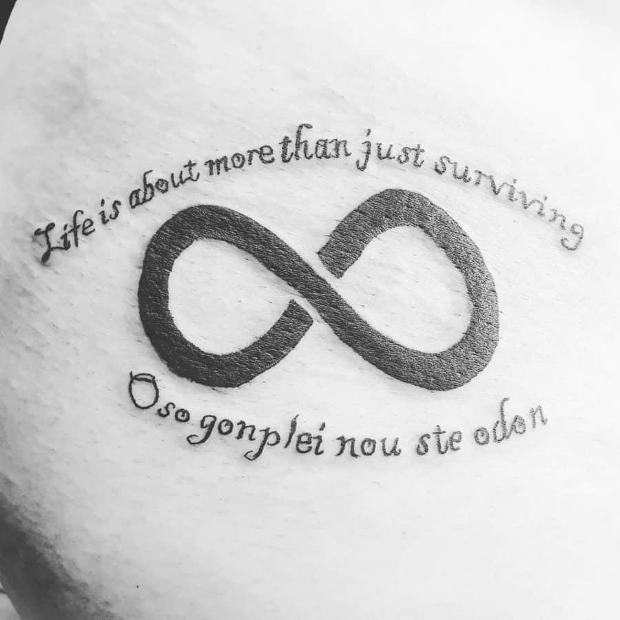 This tattoo features the phrase "Life is about more than just surviving" with the infinity symbol and "Oso gonpléi nou ste odon" below, creating a meaningful and timeless design.