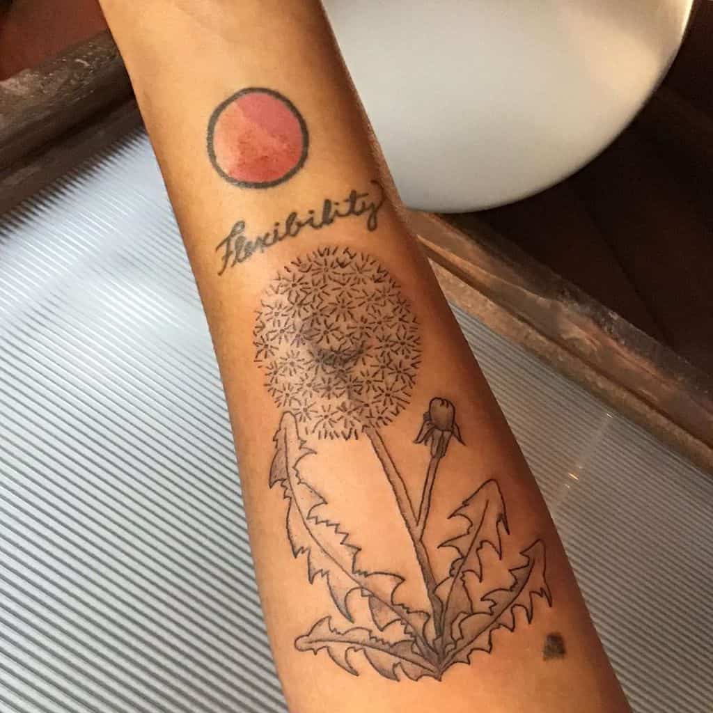 A detailed dandelion tattoo with the word "flexibility" above it, symbolizing growth and adaptability, enhanced by a subtle red circle.