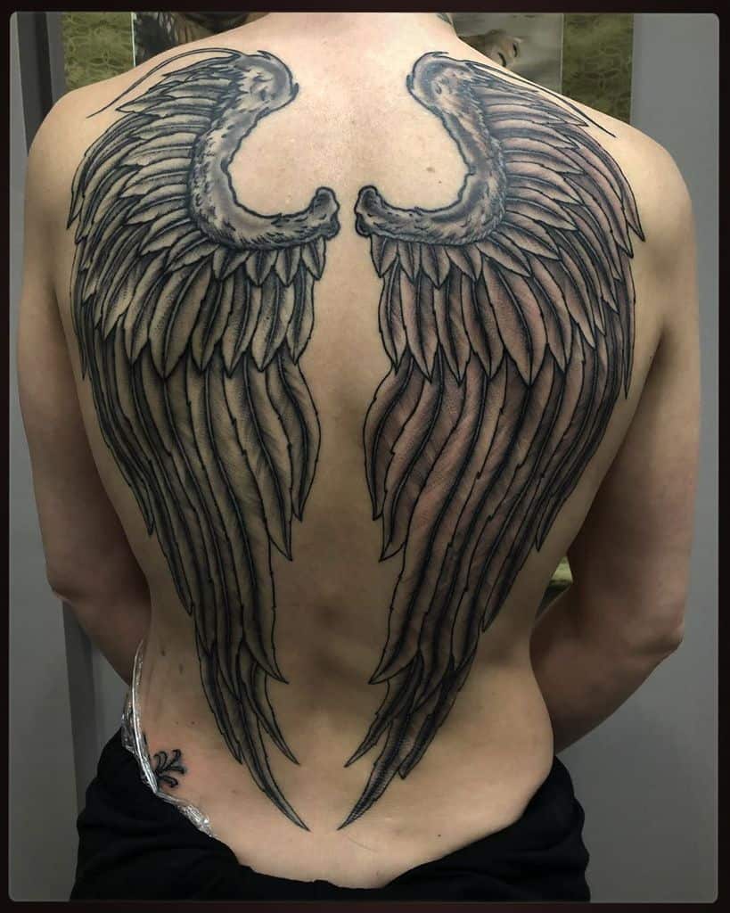 A large, detailed angel wings tattoo with intricate feather shading which makes it realistic