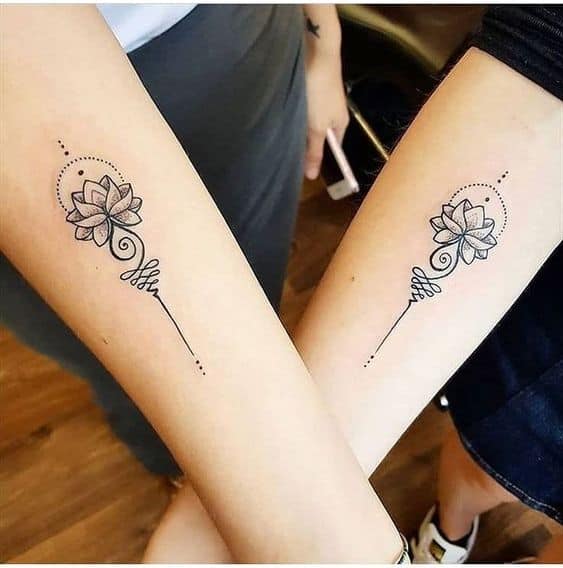 Matching Unalome tattoos with lotus flowers on forearms, symbolizing shared spiritual journeys, growth, and enlightenment.