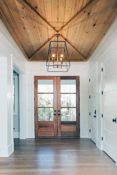 Foyer with vaulted wood ceiling, glass-paneled double doors, and a black metal pendant light.
