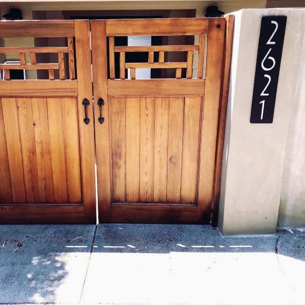 Wooden gate with geometric patterns, closed under bright sunlight, house number 2621 displayed on the right column