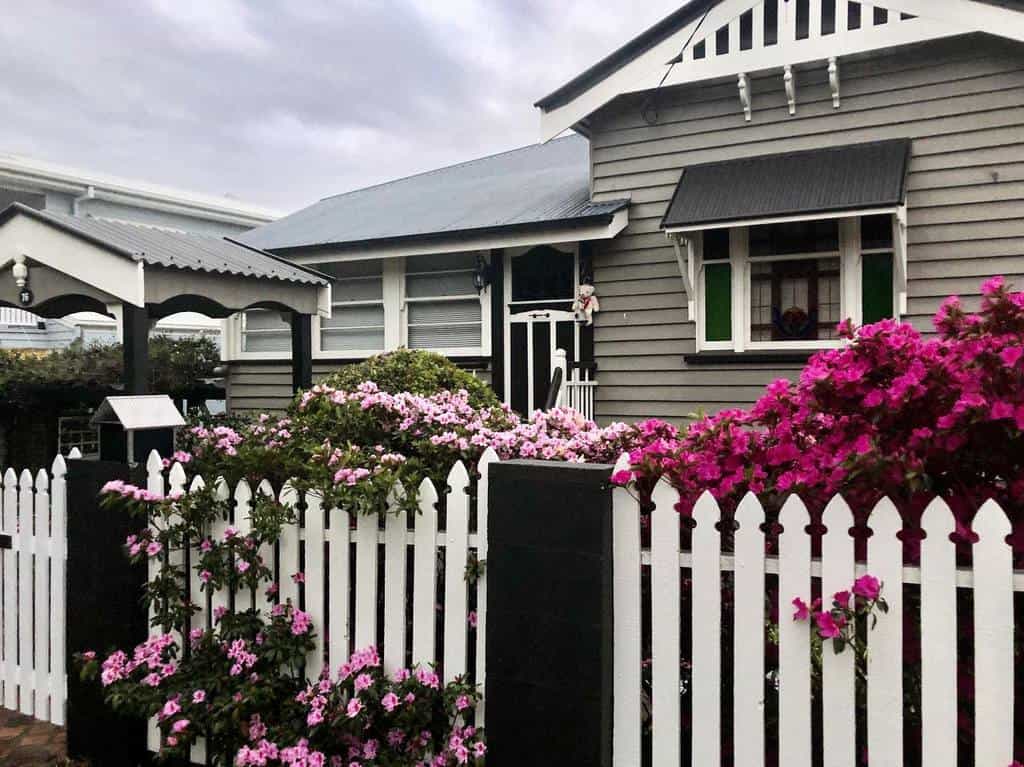 front yard flower garden gray house white picket fence pink flowers