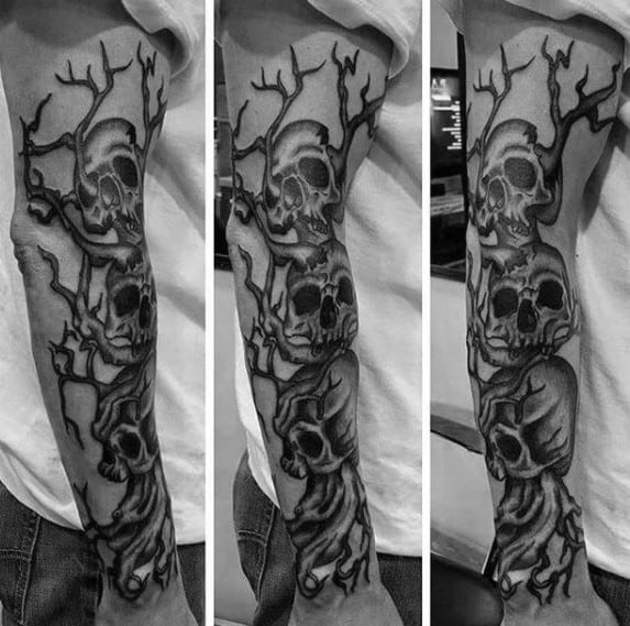 Forearm sleeve tattoo with intertwined skulls and twisted tree branches, blending dark surrealism and bold blackwork style.