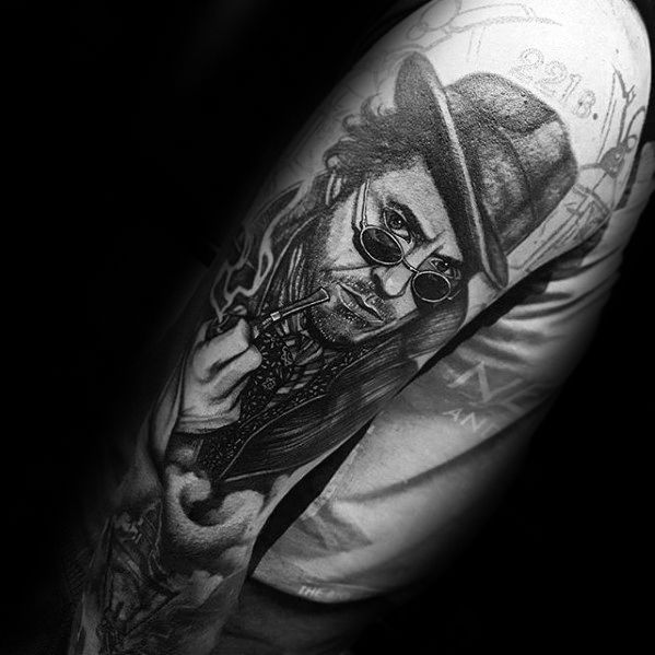 A detailed tattoo of Sherlock Holmes featuring sunglasses, a hat, and holding a pipe on someone's arm