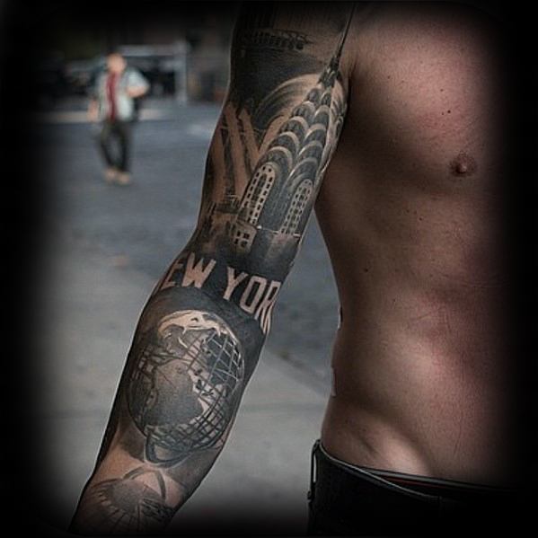 Full-sleeve black and gray tattoo featuring the Chrysler Building, globe sculpture, and bold “New York” text in a cityscape design.