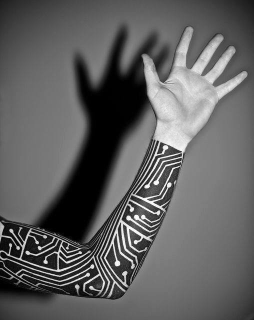 Full sleeve tattoo in black ink with bold white circuit board patterns, creating a striking tech-inspired look from wrist to elbow.