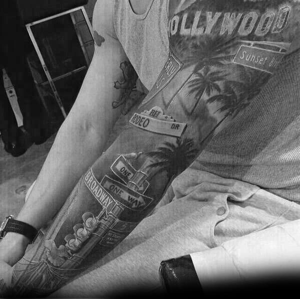 Full sleeve black and grey tattoo featuring Hollywood, Sunset Blvd, Rodeo Dr, and Broadway street signs with palm trees and city details.