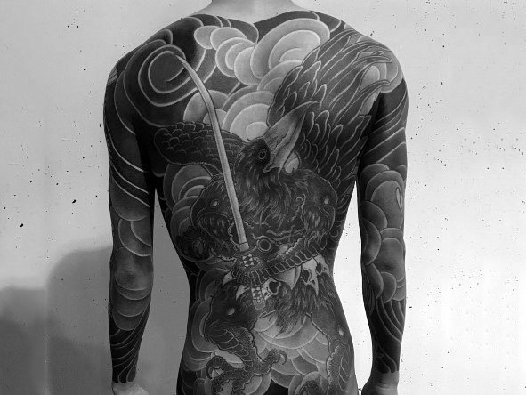 Full back Japanese-style tattoo of a fierce hawk gripping a katana, surrounded by dramatic clouds, symbolizing courage, precision, and warrior spirit.