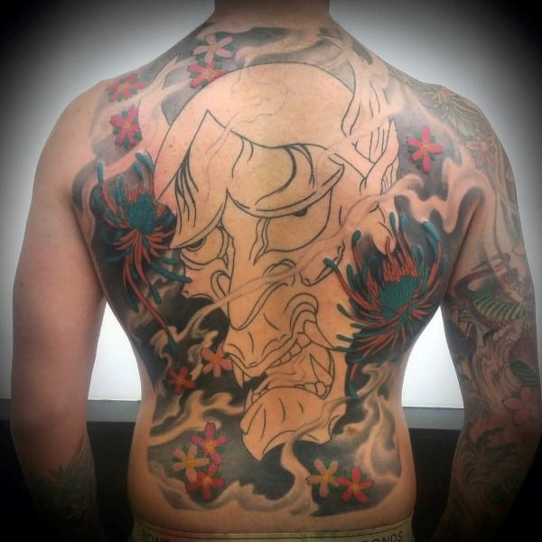 Japanese-style full back tattoo featuring an unfinished Hannya mask, swirling smoke, vibrant chrysanthemums, and red cherry blossoms