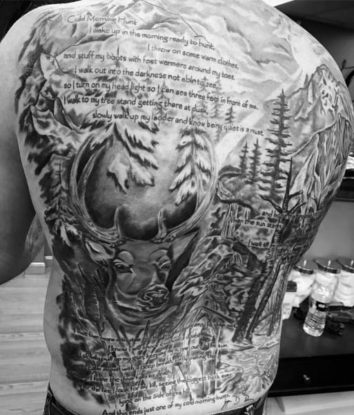 Full back tattoo featuring a detailed wilderness scene with a large deer, pine trees, mountains, and a poetic hunting quote overlaid.