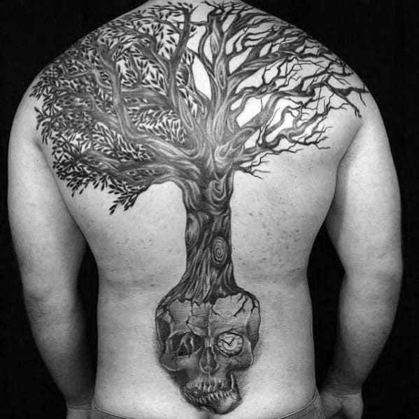 Large back tattoo of a tree growing from a cracked skull, symbolizing life emerging from death with intricate detail in roots and branches.