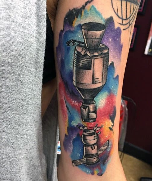 Tattoo of a spacecraft in outer space with colorful cosmic background on an arm