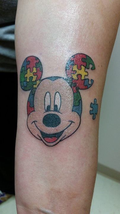 Full color tattoo of Mickey Mouse with Autism Awareness Puzzle ears, with one piece missing.
