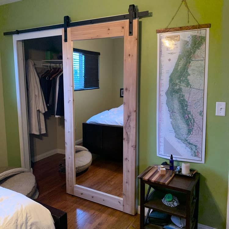 Sliding barn door with a full-length mirror leading to a small closet in a cozy bedroom.