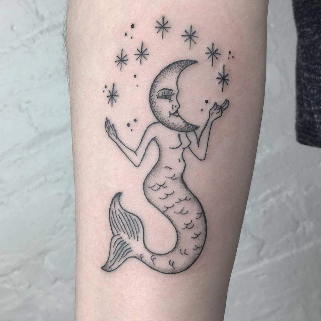 Minimalist black line tattoo of a mermaid with a crescent moon face, surrounded by stars, blending celestial and oceanic themes.