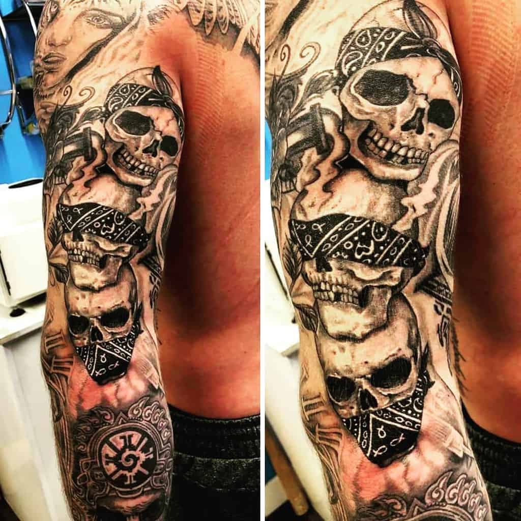 Full-sleeve tattoo of three skulls wearing bandanas, symbolizing 'Hear No Evil, See No Evil, Speak No Evil,' with intricate shading