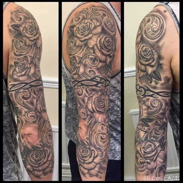 A stunning sleeve tattoo featuring roses and butterflies, beautifully rendered in black and gray tones