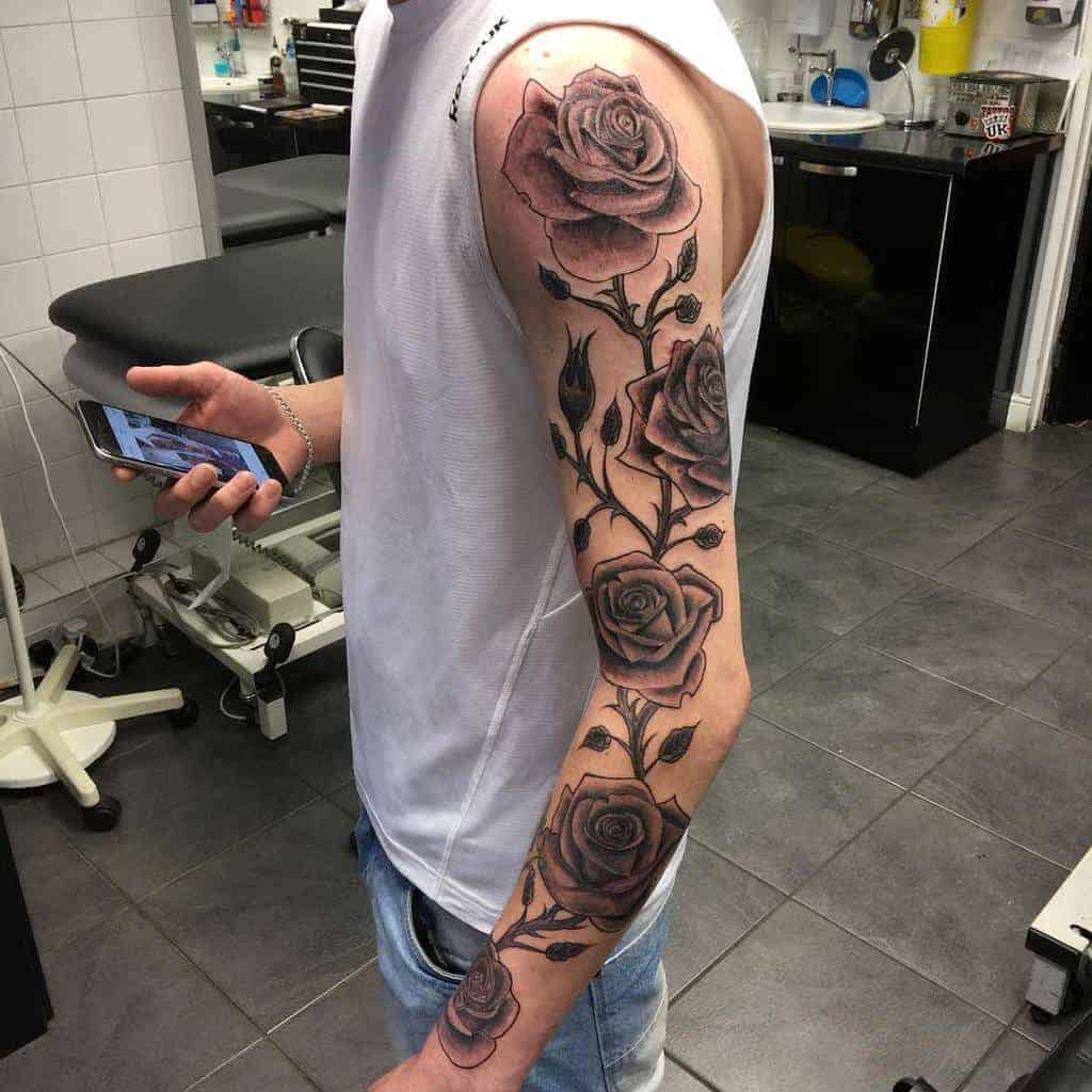 A man with a full sleeve tattoo of roses on their left arm