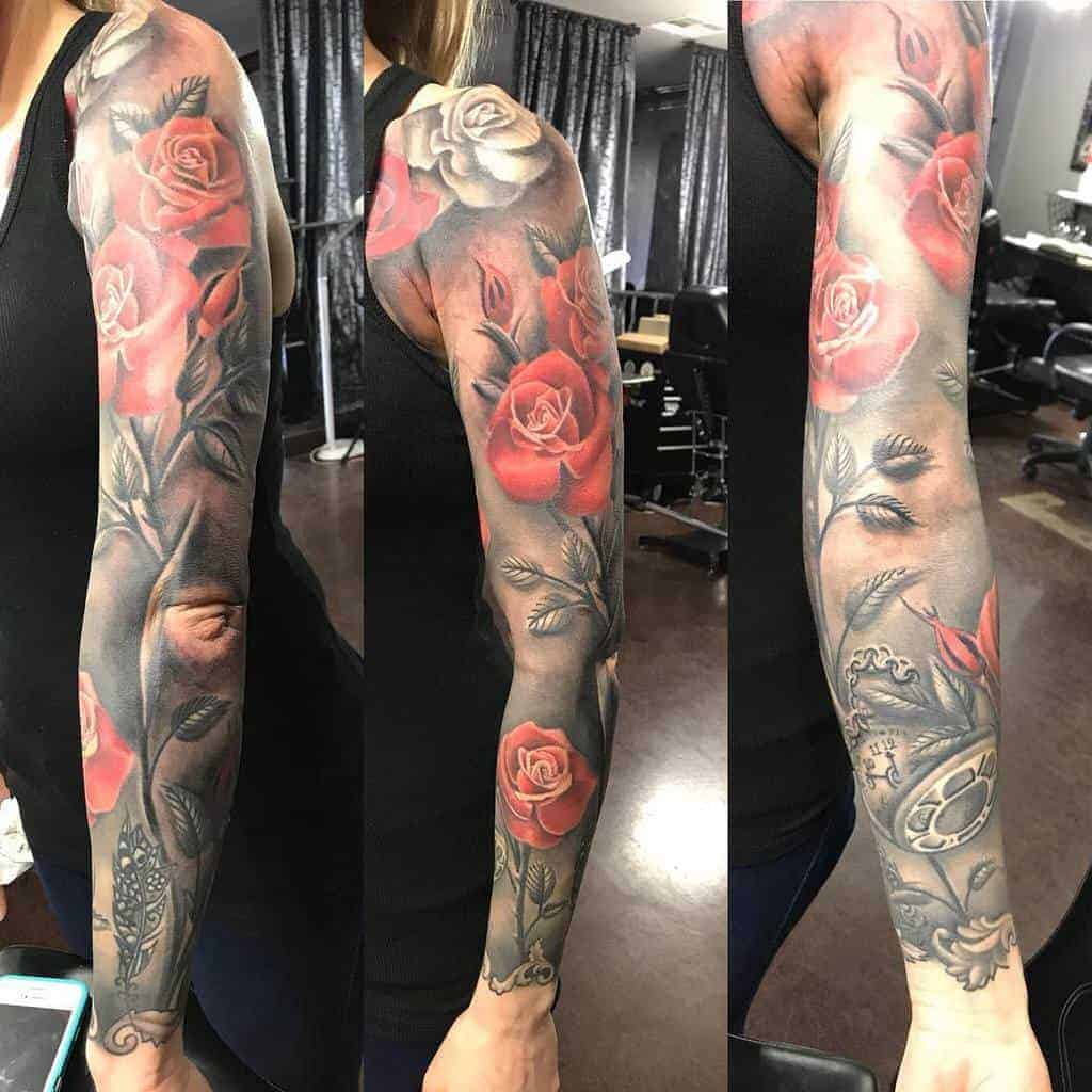 Full sleeve tattoo featuring red and white roses with detailed leaves on a woman's arm