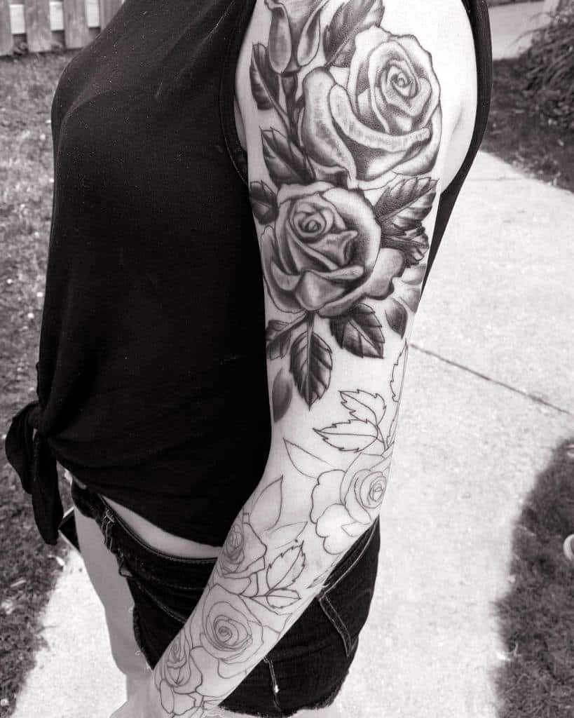 Woman's arm with a detailed black rose tattoo sleeve