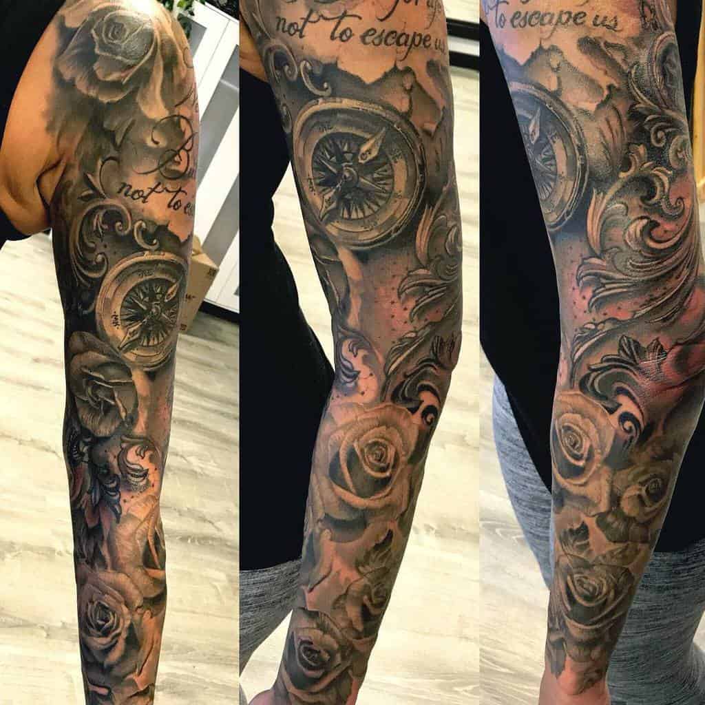 A stunning sleeve tattoo featuring roses, a compass, and intricate black and gray designs
