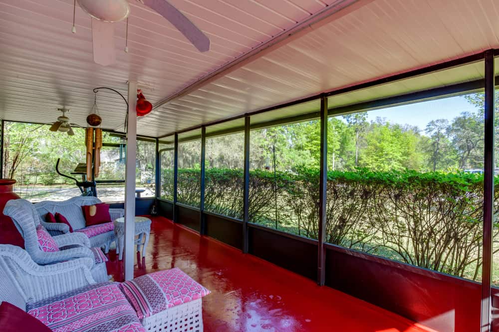 painted red floor enclosed patio wihite wicker furniture 