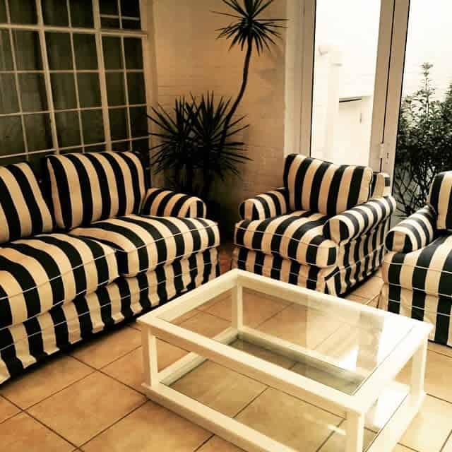 tile floor enclosed patio black and white stripe sofa and lounge chairs glass top table 