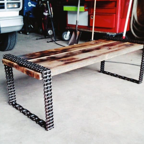 Industrial-style bench made from wooden planks and metal chains in a garage setting