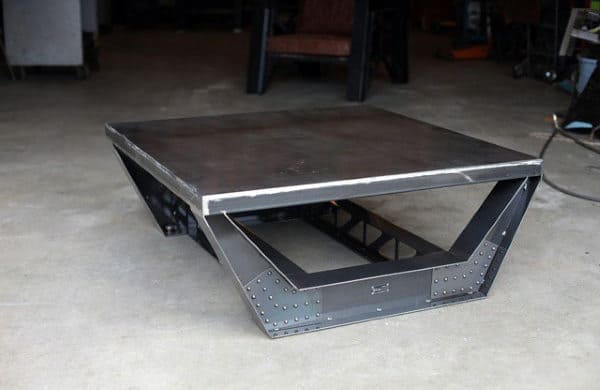 A futuristic, industrial-style metal coffee table on a concrete floor