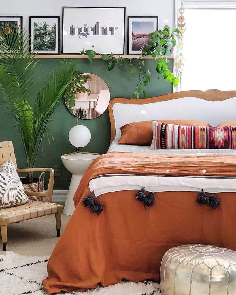 Bedroom with orange bedspread, green accent wall, and photo shelf with framed art.