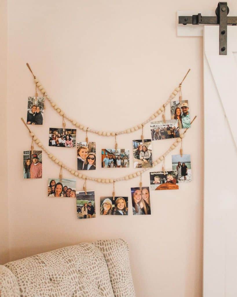 Hanging photo display with wooden beads on a soft pink bedroom wall.