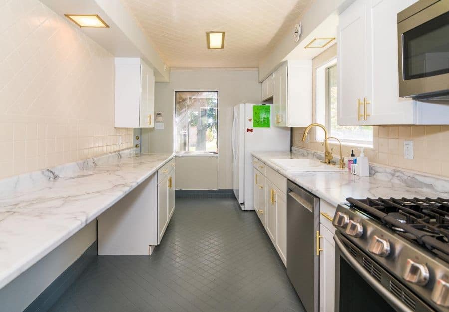 large galley kitchen with white cabinets gold accents