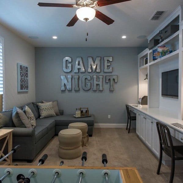 Game room with GAME NIGHT wall sign, sectional sofa, foosball table, and built-in desk area.