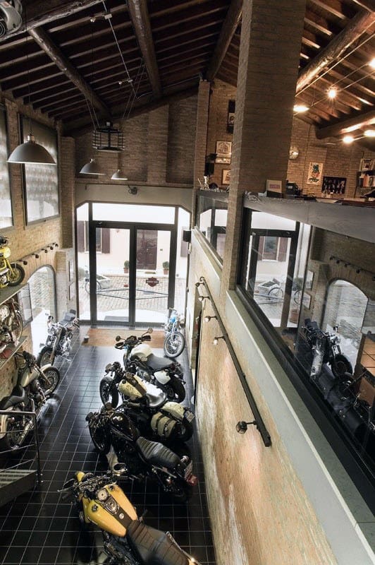 A motorcycle showroom with various bikes, featuring high ceilings, large windows, and a sleek garage vibe