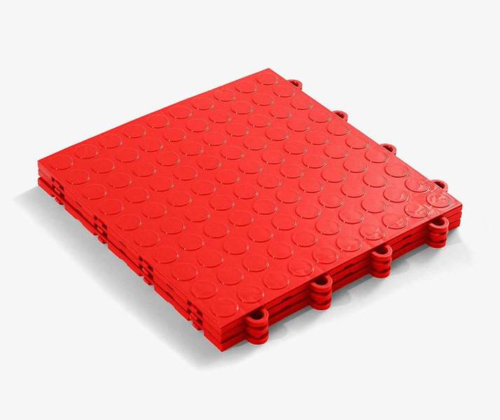Red interlocking garage flooring tiles with a textured circular pattern for durability and grip.