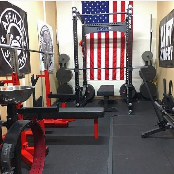 Garage gym with bench press, power rack, weight plates, and American flag wall decor.